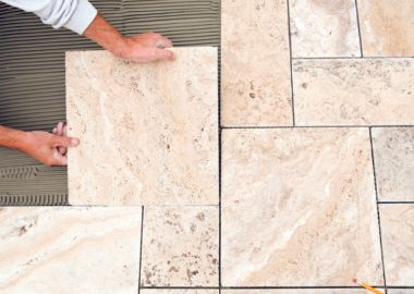 worker-places-new-tile-on-a-bathroom-floor-travertine