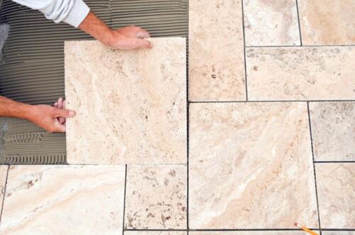worker-places-new-tile-on-a-bathroom-floor-travertine